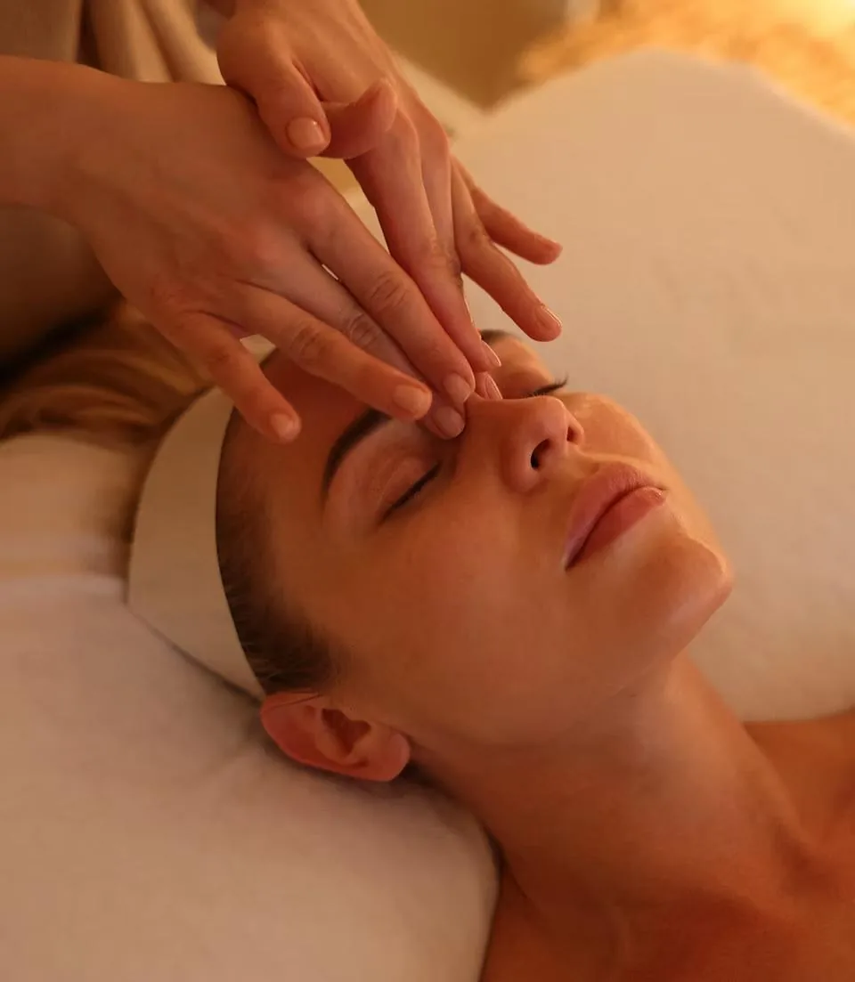 Specialist's hands resting on a client's face during a Divine Face® session